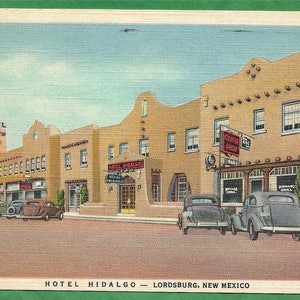 May include: A vintage postcard depicting the Hotel Hidalgo in Lordsburg, New Mexico. The hotel is a large, adobe-style building with a red tiled roof. There are several cars parked in front of the hotel, and the sign above the entrance reads "Hotel Hidalgo".