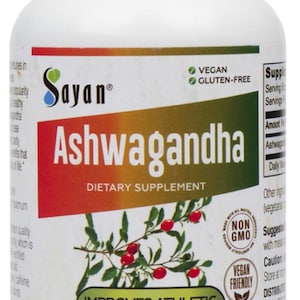 K&ouml;nnte beinhalten: Eine wei&szlig;e Flasche mit einem gr&uuml;n-goldenen Etikett, auf dem "Sayan Ashwagandha Nahrungserg&auml;nzungsmittel" steht. Die Flasche enth&auml;lt 100 vegetarische Kapseln, jede mit 500 mg Ashwagandha. Das Etikett gibt auch an, dass das Produkt vegan, glutenfrei und gentechnikfrei ist. Die Flasche steht auf einer wei&szlig;en Oberfl&auml;che.
