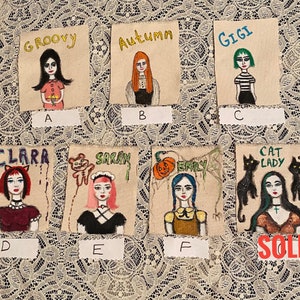 May include: Six hand-painted canvas patches with different designs and names. The patches are labeled with letters A through F. The patches feature a variety of designs, including a girl with a flower, a girl with a pumpkin, a girl with a cat, a girl with a teddy bear, a girl with a spider web, and a girl with a cat. The patches are all on a white background.