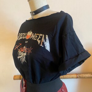 May include: Black t-shirt with a graphic print of the word "Halloween" with an apple and a skull design. The shirt has a distressed look and is worn with a black leather choker and a red leather skirt.