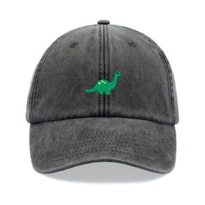 May include: A black washed cotton baseball cap with an embroidered green dinosaur on the front.