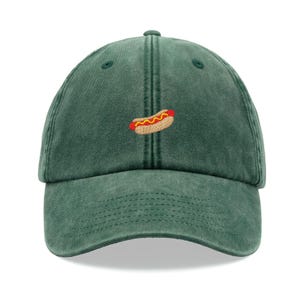 May include: A green baseball cap with a small embroidered hot dog on the front.