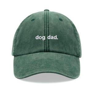 Può includere: Un berretto da baseball verde con la scritta bianca "dog dad.". Il berretto ha una visiera curva e una chiusura con cinturino in tessuto sul retro. Il cappello è realizzato in un materiale morbido e usurato.