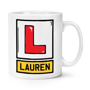 May include: White ceramic mug with a red "L" in a black square and the name "LAUREN" in a yellow rectangle.