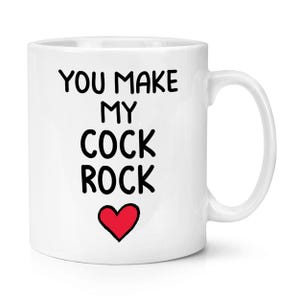 Puede incluir: Taza de cerámica blanca con el texto "YOU MAKE MY COCK ROCK" en negro, con un corazón rojo debajo. La taza tiene un asa curva y está diseñada para bebidas calientes.