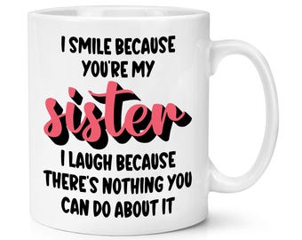 May include: White ceramic mug with a black and pink design. The text on the mug reads "I smile because you're my sister. I laugh because there's nothing you can do about it."