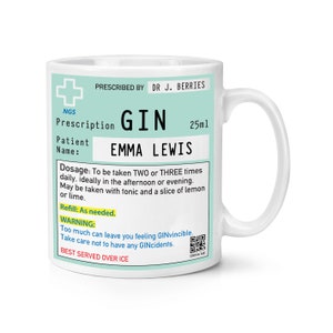 Könnte beinhalten: Eine weiße Keramiktasse mit einem blau-weißen Design. Die Tasse zeigt ein Rezept für "GIN" mit dem Patientenname "EMMA LEWIS" und einer Dosierung von 25 ml. Das Etikett enthält Anweisungen zur Einnahme von "GIN" und eine Warnung, dass "Zu viel "GIN" Sie unbesiegbar fühlen lassen kann."