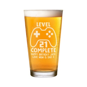 May include: A clear glass beer stein with a white design that says "Level 21 Complete Happy Birthday Jack Love Mum & Dad X". The design also includes a video game controller graphic.