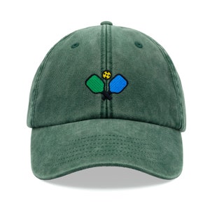 May include: A dark green, adjustable, cotton baseball cap with an embroidered design of two pickleball paddles and a ball.