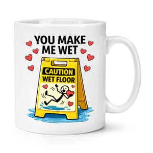 Puede incluir: Taza de cerámica blanca con un diseño humorístico. La taza presenta el texto "YOU MAKE ME WET" sobre un letrero amarillo "CAUTION WET FLOOR" con un muñeco de palo resbalando y sosteniendo un corazón. Corazones rojos dispersos.