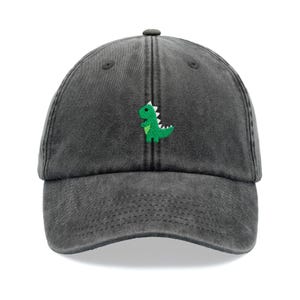 Könnte beinhalten: Eine schwarze, gewaschene Baseballkappe aus Baumwolle mit einem grünen gestickten Dinosaurier auf der Vorderseite.
