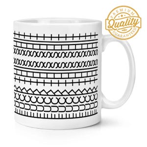 Może przedstawiać: Biały ceramiczny kubek z czarnym geometrycznym wzorem. Wzór zawiera poziome linie, zygzaki i inne kształty. Złota naklejka "Premium Quality Guaranteed" znajduje się na uchwycie.
