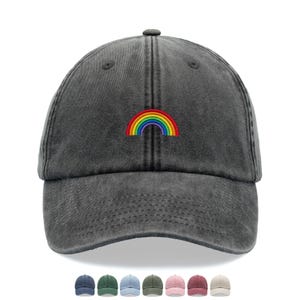 Peut inclure: Une casquette de baseball gris anthracite à la texture délavée, ornée d'un petit arc-en-ciel brodé au centre du panneau avant. La casquette présente une visière incurvée, des œillets cousus et un bouton sur le dessus, avec d'autres coloris en dessous.