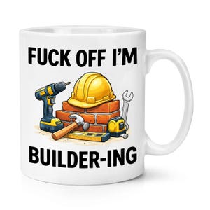 Op de afbeelding: Witte keramische mok met de tekst "FUCK OFF I'M BUILDER-ING". De mok toont illustraties van bouwmachines, waaronder een boor, hamer, waterpas, rolmaat, moersleutel en een gele helm.
