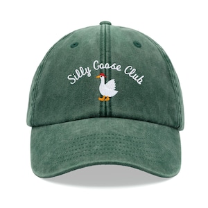 May include: A green baseball cap with the text "Silly Goose Club" embroidered on the front. A white goose with a red hat is embroidered in the centre of the text.