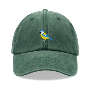Peut inclure: Une casquette de baseball verte avec un petit oiseau bleu brodé avec des accents jaunes.