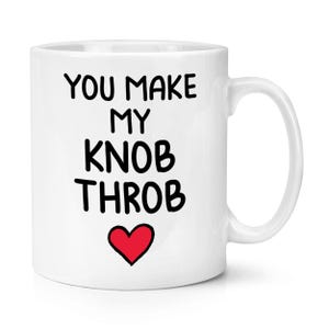 Puede incluir: Taza de cerámica blanca con el texto "YOU MAKE MY KNOB THROB" en negro, con un corazón rojo debajo. La taza tiene un asa curva.