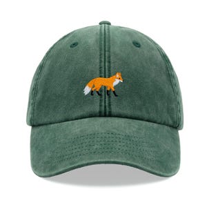 May include: A green baseball cap with an embroidered orange fox design.