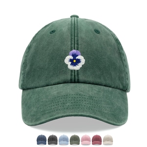 May include: A green cotton baseball cap with an embroidered purple and white pansy flower.