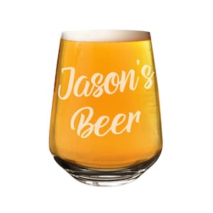 Puede incluir: Una jarra de cerveza de vidrio transparente con un borde escarchado llena de cerveza de color amarillo dorado. La jarra está grabada con el texto "Jason's Beer".