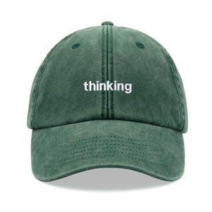 May include: A dark green baseball cap with the word "thinking" embroidered in white on the front.