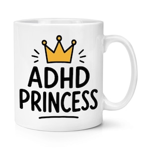 May include: A white ceramic mug featuring a yellow crown graphic above the black text "ADHD PRINCESS" with a small horizontal line underneath. The design is centred on the front of the mug, which has a standard handle on the right side.