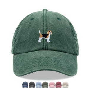 May include: A green baseball cap with a worn look. It has an embroidered beagle dog design in black, white, and brown. The image also shows a selection of other cap colours.