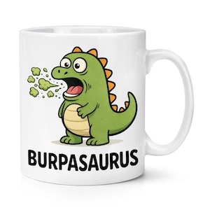 Puede incluir: Taza de cerámica blanca con una ilustración de dibujos animados de un dinosaurio verde. El dinosaurio, con púas naranjas, eructa gas verde. El texto "BURPASASAURUS" está impreso en negro. La taza tiene un asa blanca.