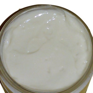 May include: A close-up of a white, creamy substance in a clear glass jar.