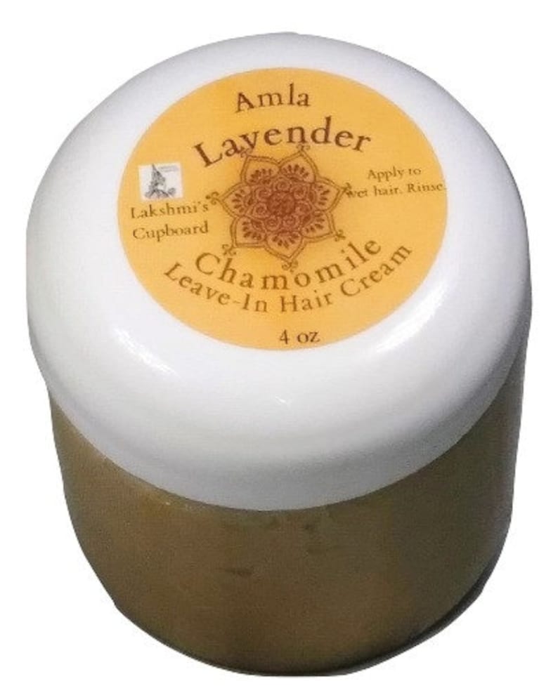 May include: A white jar with a gold lid and label. The label says "Amla Lavender Chamomile Leave-In Hair Cream" and "Lakshmi's Cupboard". The jar contains a light brown cream and is 4 oz.