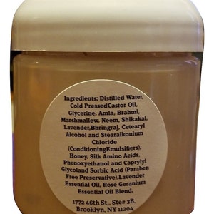 May include: A white plastic jar with a brown label listing the ingredients of a hair care product. The label includes the text "Ingredients: Distilled Water, Cold Pressed Castor Oil, Glycerine, Amla, Brahmi, Marshmallow, Neem, Shikakai, Lavender, Bhringraj, Cetearyl Alcohol and Stearalkonium Chloride (Conditioning Emulsifiers), Honey, Silk Amino Acids, Phenoxyethanol and Caprylyl Glycoland Sorbic Acid (Paraben Free Preservative), Lavender Essential Oil, Rose Geranium Essential Oil Blend. 1772 46th St., Ste# 3B, Brooklyn, NY 11204"