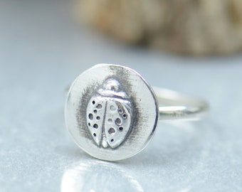 May include: A silver ring with a ladybug design. The ladybug is detailed with spots and has a textured finish.