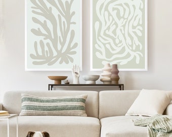 Puede incluir: Un sofá seccional blanco con una manta de tiro verde y un perro blanco acostado en el suelo frente a él. Dos impresiones de arte abstracto enmarcadas con un esquema de color verde claro y blanco cuelgan en la pared sobre el sofá.