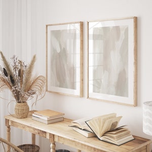 以下が含まれることがあります： 明るい木製の仕上げのコンソールテーブル。テーブルには2つの棚があり、ドライフラワーの入った花瓶、本、額装された抽象的なプリントで飾られています。