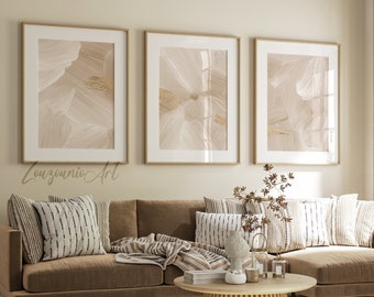 May include: A brown sectional sofa with a white and black striped throw pillow and a beige throw blanket. Three framed abstract art prints with beige and gold tones hang on the wall above the sofa. A wooden coffee table with a woven design sits in front of the sofa.