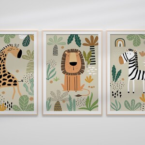 Op de afbeelding: Drie ingelijste prints met een jungle thema. Elke print toont een ander dier: een giraffe, een leeuw en een zebra. De prints zijn geplaatst tegen een achtergrond van groen en bruin gebladerte.