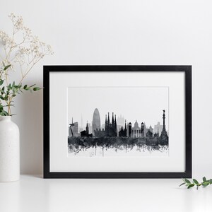 K&ouml;nnte beinhalten: Schwarz-wei&szlig;es Aquarell-Stadtbild von Barcelona, Spanien. Der Druck ist in einem schwarzen Rahmen gerahmt und an einer wei&szlig;en Wand ausgestellt.