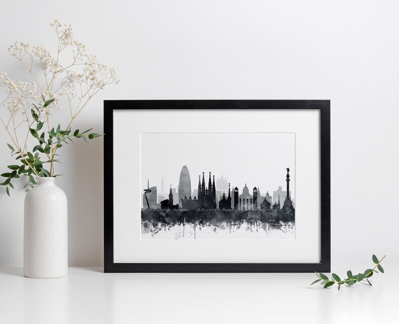 K&ouml;nnte beinhalten: Schwarz-wei&szlig;es Aquarell-Stadtbild von Barcelona, Spanien. Der Druck ist in einem schwarzen Rahmen gerahmt und an einer wei&szlig;en Wand ausgestellt.