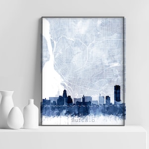 Peut inclure: Une illustration aquarelle de l'horizon de Buffalo, New York, dans des tons de bleu. Les bâtiments de la ville sont en silhouette sur un fond bleu clair, avec une carte de la ville en arrière-plan. Le mot "Buffalo" est imprimé en blanc en bas de l'image.