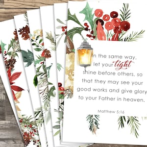 Op de afbeelding: Set van 6 printbare kerstkaarten met een aquarel-illustratie van een lantaarn met hulst en bessen. De kaarten bevatten de Bijbeltekst Mattheüs 5:16: "Laat uw licht zo schijnen voor de mensen, dat zij uw goede werken zien en uw Vader, die in de hemel is, eren."
