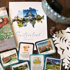 以下が含まれることがあります： スイスの国別学習ユニットのための教育資料のコレクション。資料には、ヨハンナ・シュピリ著の「ハイジ」という本、スイスの地図、スイスの牛、ケーブルカー、チューリッヒ、ベルン、スイスアーミーナイフに関する画像とテキストが書かれたフラッシュカードがいくつか含まれています。