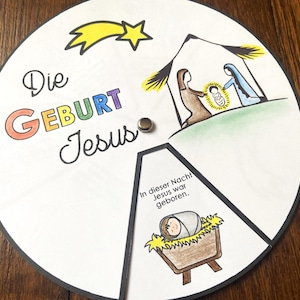 Puede incluir: Una manualidad circular ilustrada con temática navideña con las palabras "Die Geburt Jesus" en letras coloridas. La imagen representa la escena de la Natividad con María, José y el niño Jesús, y una estrella fugaz.
