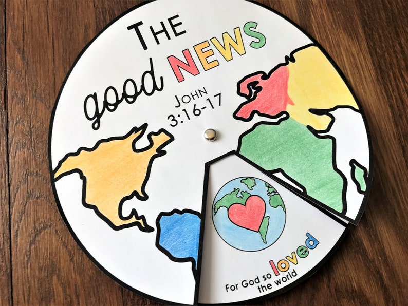 Puede incluir: Una rueda de papel colorida con un mapa del mundo dividido en secciones. La rueda tiene las palabras "The good news" y "John 3:16-17" escritas en ella. El centro de la rueda tiene una imagen de un globo terr&aacute;queo con un coraz&oacute;n rojo y las palabras "For God so loved the world".
