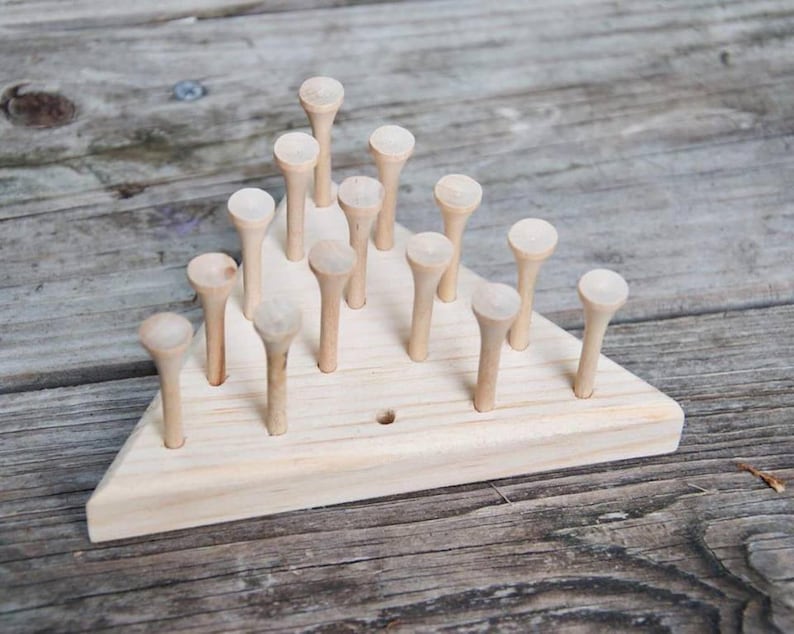 May include: A wooden triangular game board with 15 wooden pegs arranged in a pyramid shape. The pegs are all the same size and shape, and they are made of natural wood.