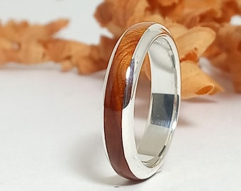 May include: A silver band ring with a thin strip of wood inlay. The wood is a rich brown colour with a natural grain pattern.