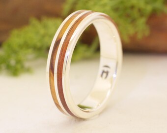 May include: A silver band with two thin strips of wood inlay. The band is engraved with the letter "E".