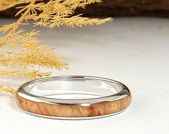 May include: A silver ring with a thin band of wood inlay. The wood is a light brown colour with a natural grain pattern.
