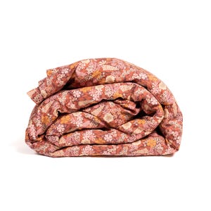May include: A folded floral duvet cover in a rust orange color with a pink and white floral pattern.