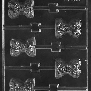 May include: A clear plastic mould for making chocolate lollipops. The mould has five cavities, each shaped like a woman's torso. The mould is designed to create lollipops with a stick attached.