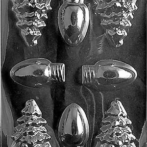 May include: A black and white plastic mold for making chocolate Christmas ornaments. The mold features six cavities: three Christmas trees, two light bulbs, and one larger light bulb.